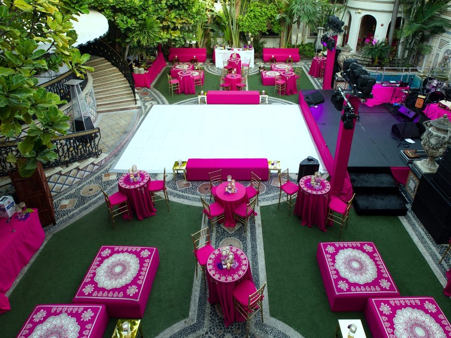 Courtyard by day, with lounge seating, cocktail tables, a dance floor, a stage, and a bar laid out